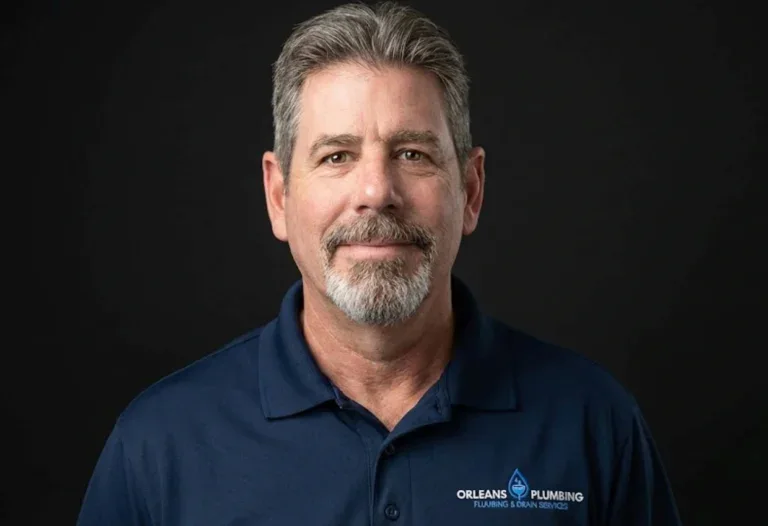 Middle-aged man with gray hair and beard wearing a blue "Orleans Plumbing" polo shirt, posing against a plain dark background—representing a trusted plumber in Ottawa.